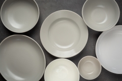 white round empty plates and bowls on dark background